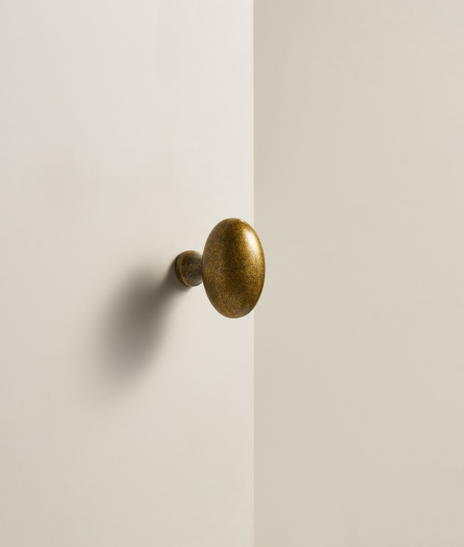 Bouton Oliena de forme ovoïde en finition bronze sur une façade claire